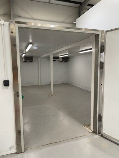 Empty industrial room with white walls and a large doorway.