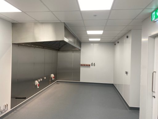 Clean, empty kitchen space with stainless steel appliances and grey flooring.