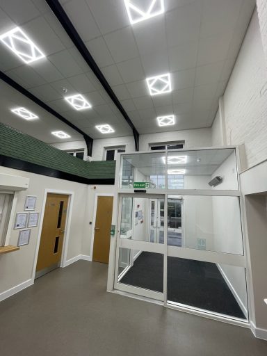 Modern indoor space with glass entrance, high ceilings, and bright lighting.