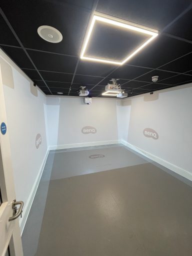 Empty, well-lit room with grey flooring and a modern ceiling design.